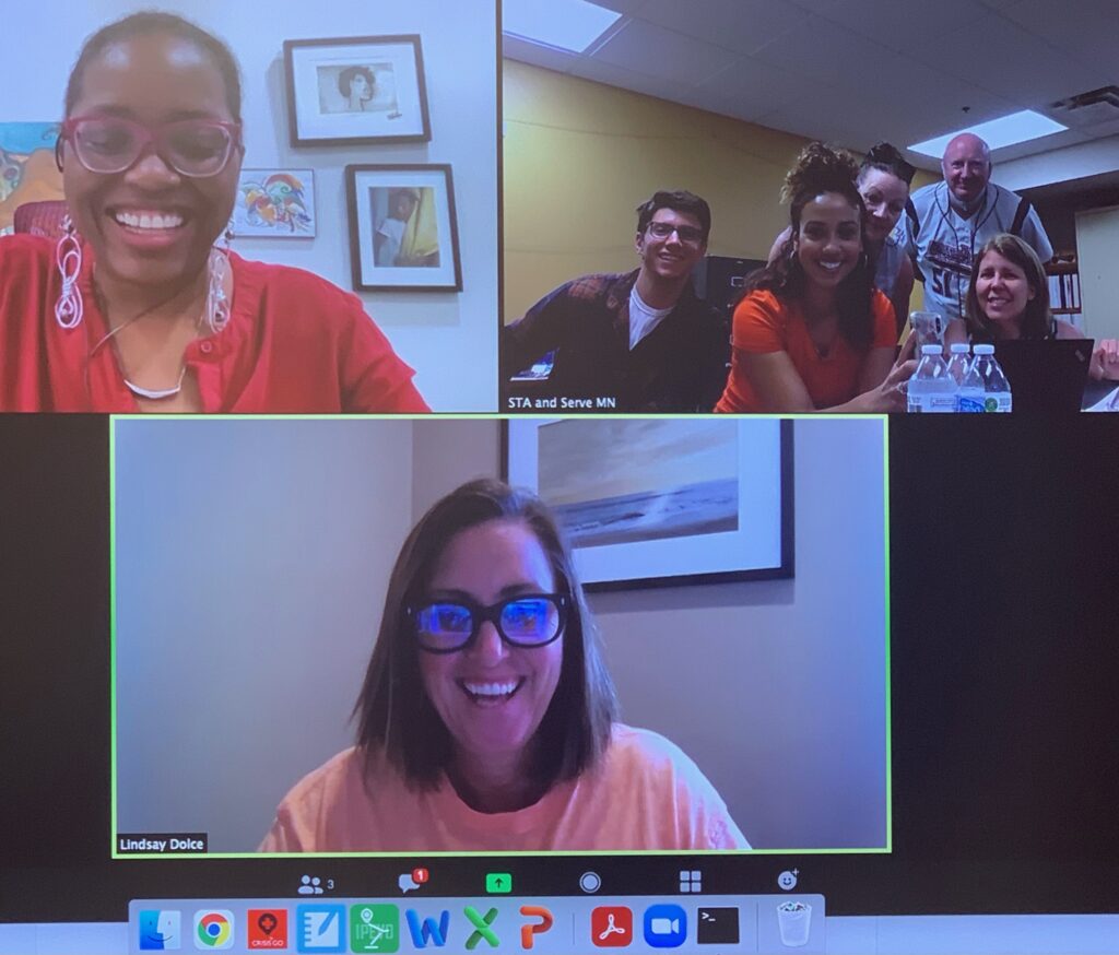 Screenshot of video call with three screens. Two have one smiling person each. The third has a group of people.